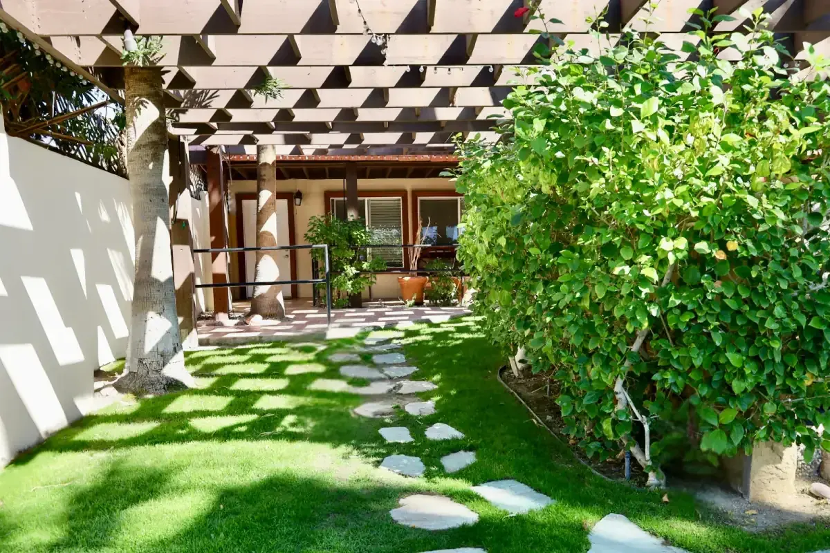 A shaded garden path beneath a wooden pergola.