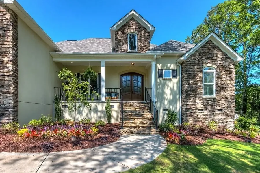 House Exterior with Stone Accents and Landscaped Entry Front exterior of a large house with stone accents, a covered porch, landscaped flower beds, and a curved walkway